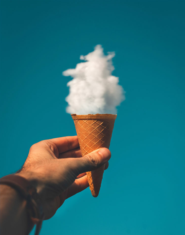 A Hand holding a ice cream cone with a cloud in it