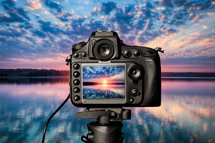 A dslr camera viewfinder shows a sunset over water