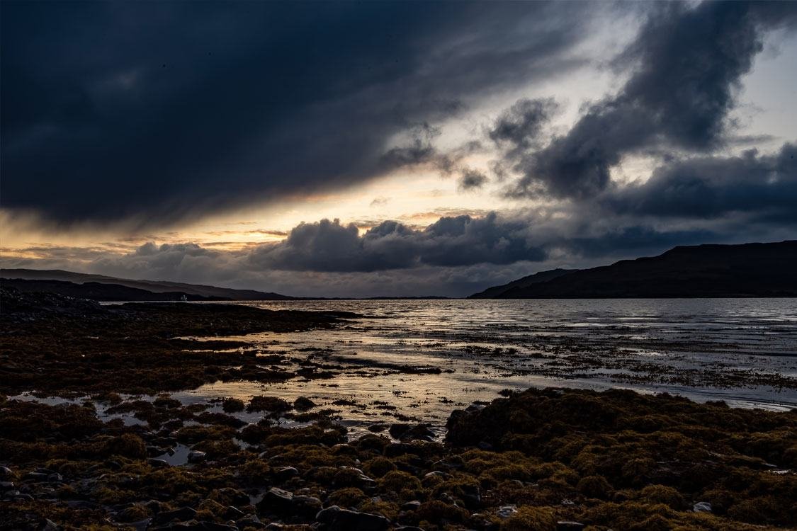 Storm cloud over a rocky shoreline at dusk